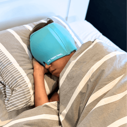 Barn som sover med turkos huvudvärksmössa från My Happy Head som ger kylande lindring vid huvudvärk, smärta och spänningar.